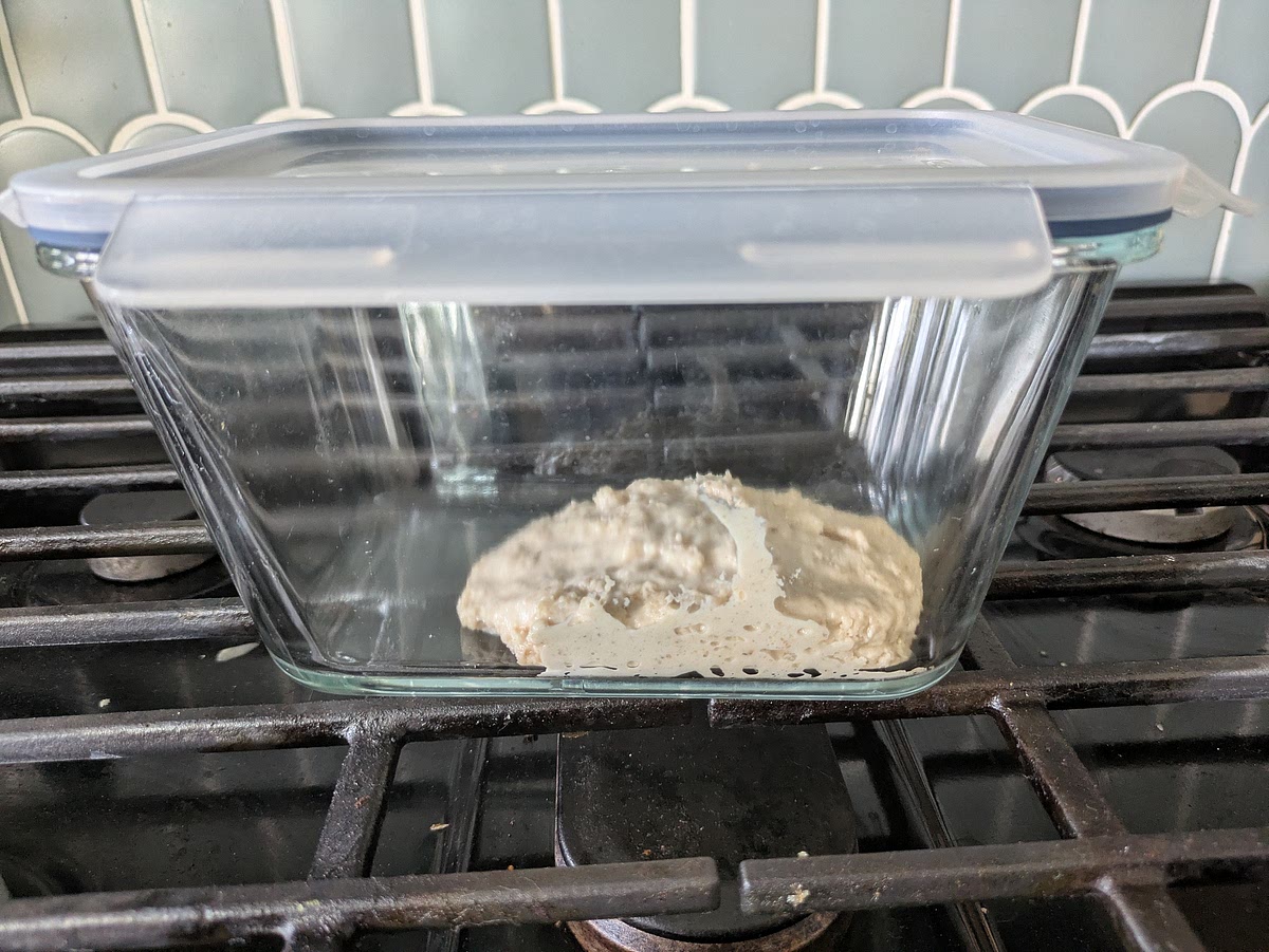 Clean Autolyse (30–45 Minutes)
In a large mixing bowl, whisk together 240g warm water, 170g sweet stiff levain, 70g allulose, lemon zest, lemon extract, and almond extract until the levain breaks down into a milky fluid.
Add 400g bread flour and 50g whole wheat flour. Mix with wet hands or a spatula until all flour is hydrated.
Cover and rest for 30–45 minutes to establish strong gluten bonds before introducing any fats.