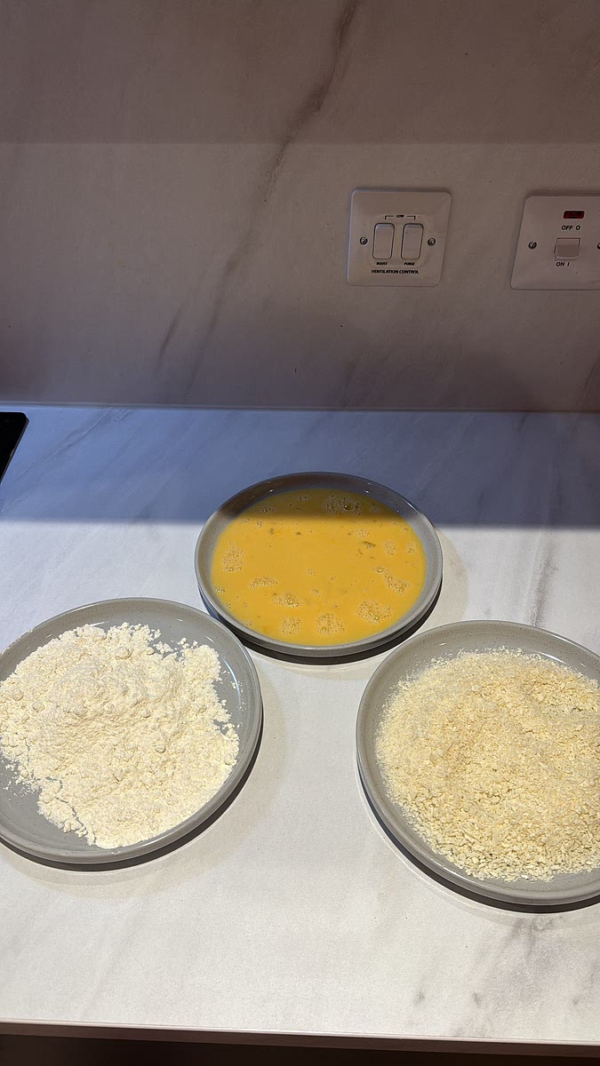 Prepare three separate dishes. Add the plain flour to the first. Add the beaten eggs to the second. In the third, combine the panko breadcrumbs and 30g Parmesan.