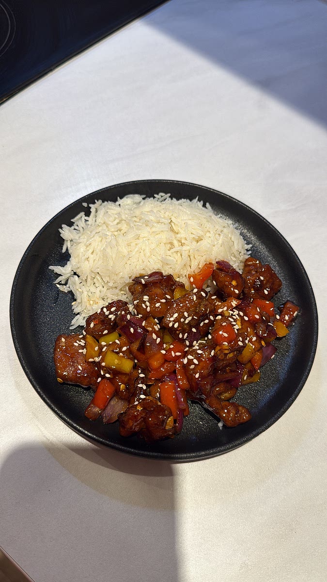 Pack the coconut rice into a small bowl and flip it onto your plate for that neat dome. Spoon the crispy sweet & spicy chicken, peppers and onions alongside/partially over the rice. Finish with chilli flakes and spring onion/sesame seeds if you’ve got them.