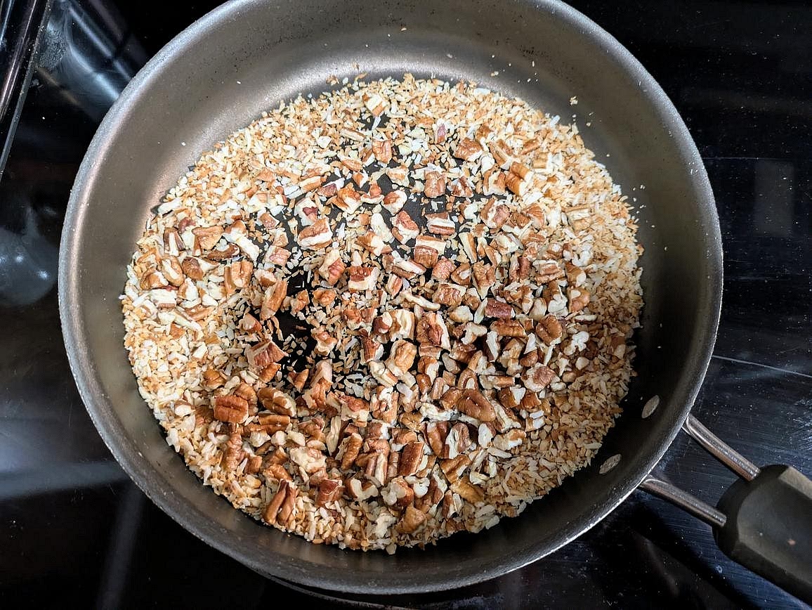 Add chopped pecans and coconut flakes to a dry pan over medium heat. Toast for about 3 minutes, or until fragrant and lightly browned.