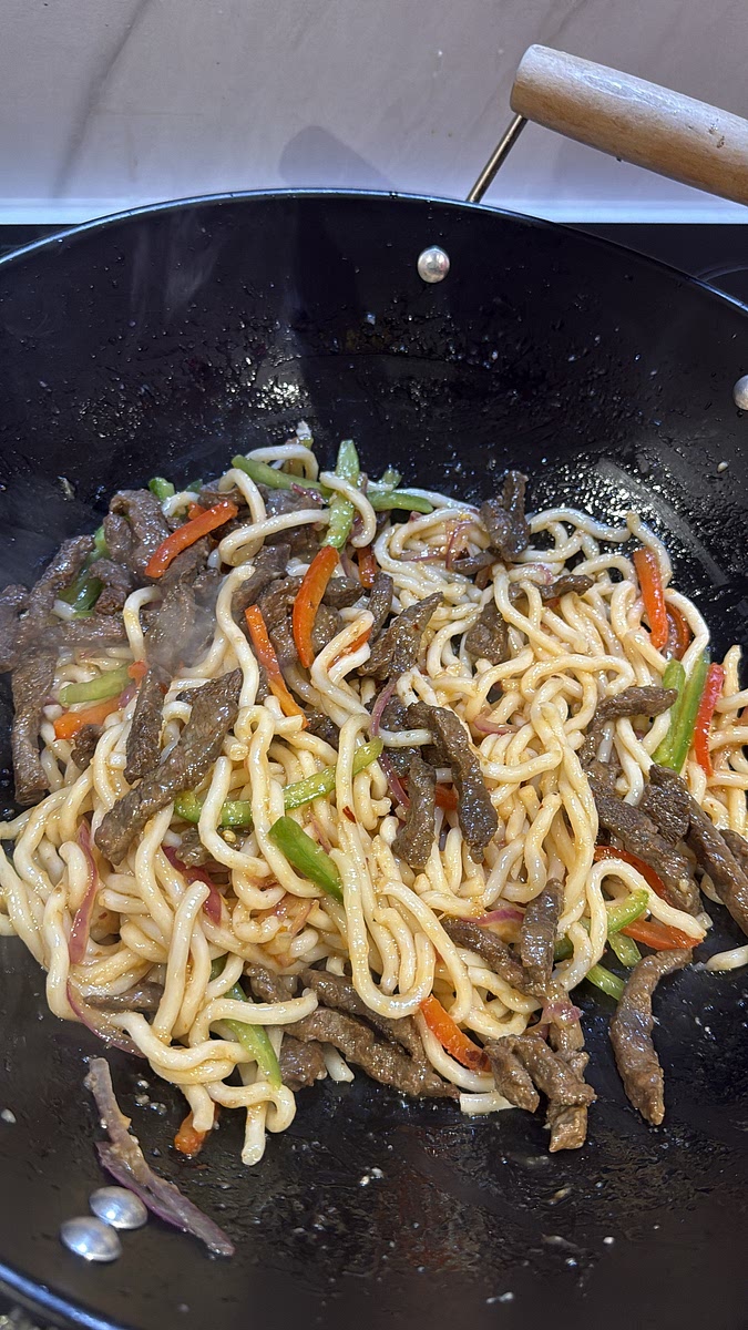 Return your beef — including any juices — to the pan. Toss everything together for another 30–60 seconds, just until the beef is hot and every noodle is coated in that glossy garlic sauce.