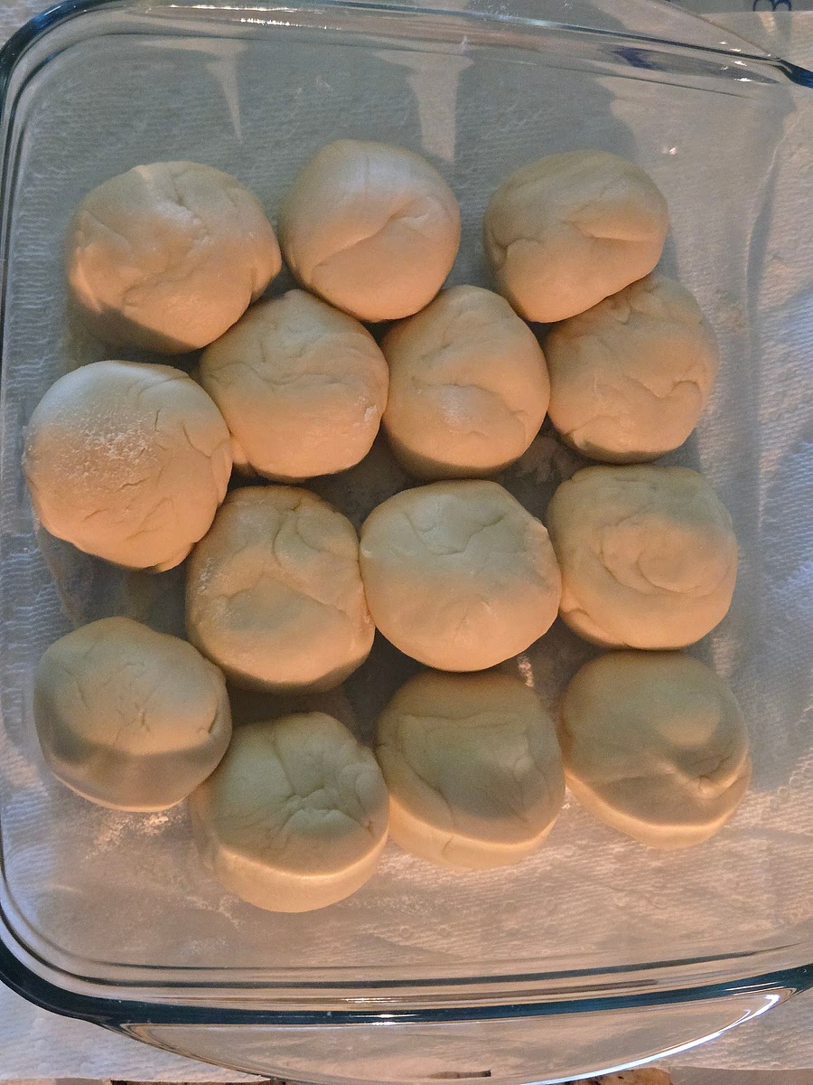 Once ready, start tearing off small segments and rolling it into equal sized balls. Add them to lightly floured tray. Make sure to keep them covered while working with the dough.