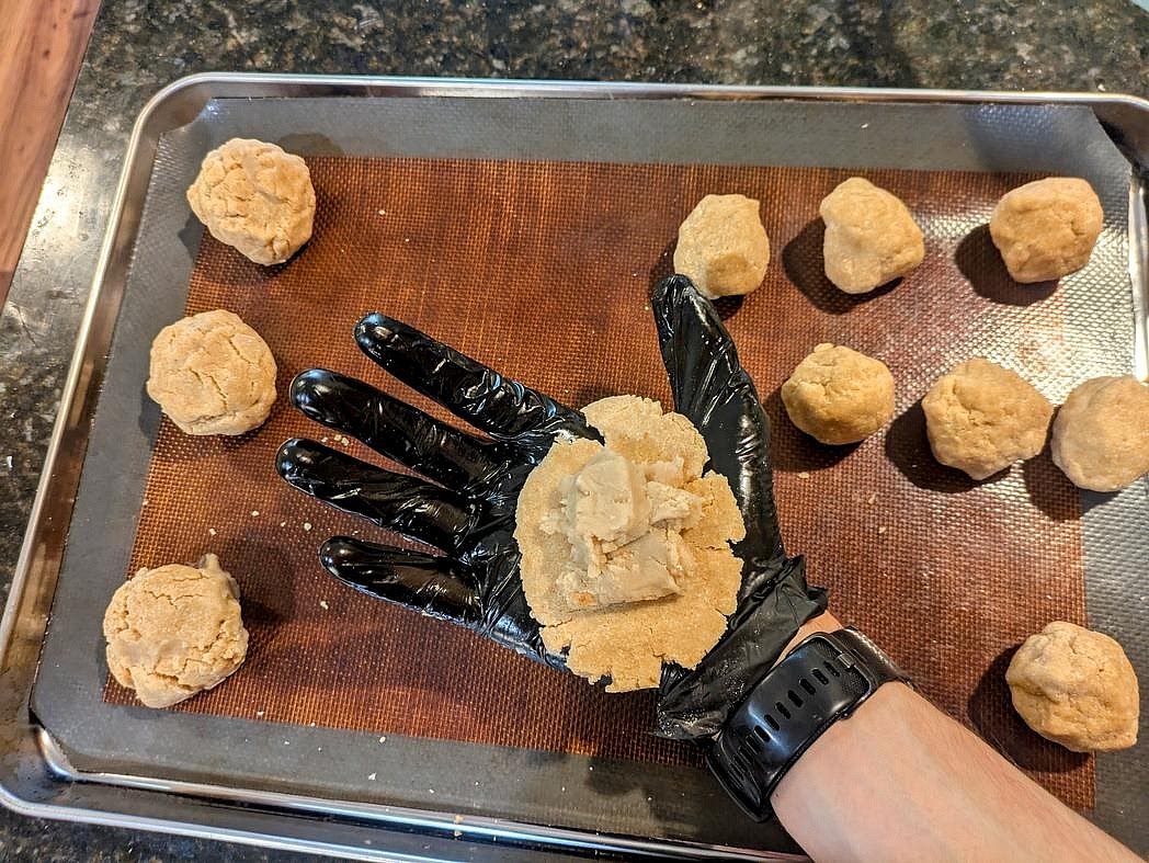 Flatten out a dough ball between your palms, and add a 20 g (~1.5 tbsp) ball of filling to the center. Carefully wrap the dough around the filling without tearing it, making sure to close up any edges. Place onto the pan, seam side down, and shape into a round, circular disk. Repeat for all mooncakes.