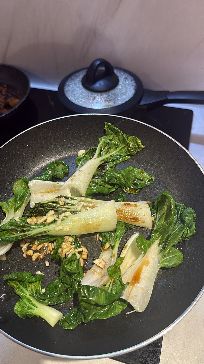 Heat the oil in a frying pan and add the pak choi Cook for 2–3 minutes. Add the chopped garlic and fry briefly before adding the soy sauce and a small splash of water. Cook for another 1–2 minutes until tender.