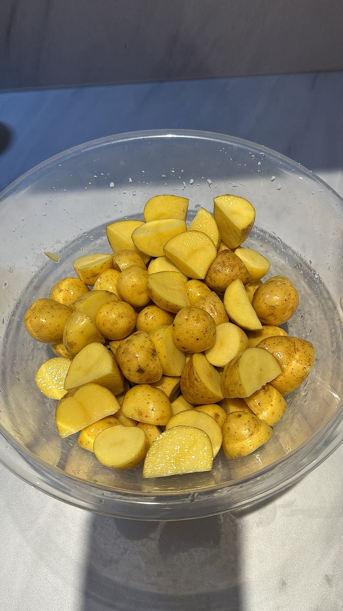 While the chicken is roasting, wash and halve the baby potatoes.