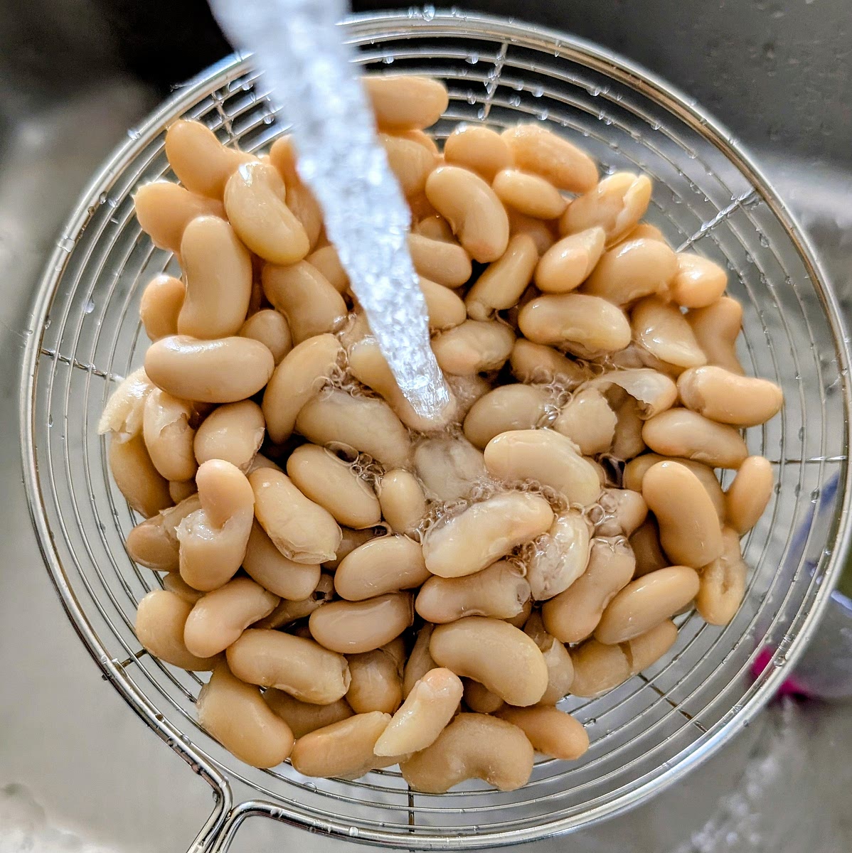 While the onions fry, empty the contents of the cannellini beans tin into a sieve and rinse them well under the tap. You should be left with 240g rinsed cooked beans.
