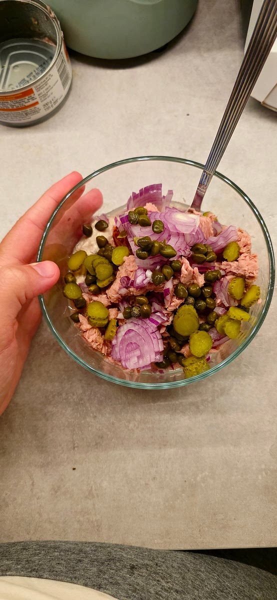 Voeg 1 blik tonijn en 1 potje delio tonijnsalade samen.
Doe er naar wens kappertjes bij.
Voeg het ajuintje toe.
