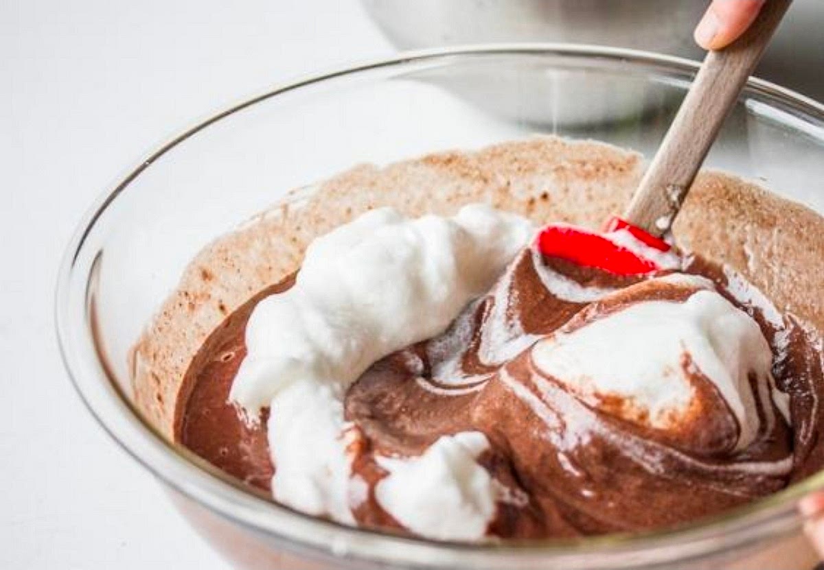 Fold the mixtures together
Stir about one-third of the whipped whites into the chocolate base to lighten it. Gently fold in the remaining whites with a spatula, turning the bowl as you go. Stop when no large white streaks remain; don't overmix.