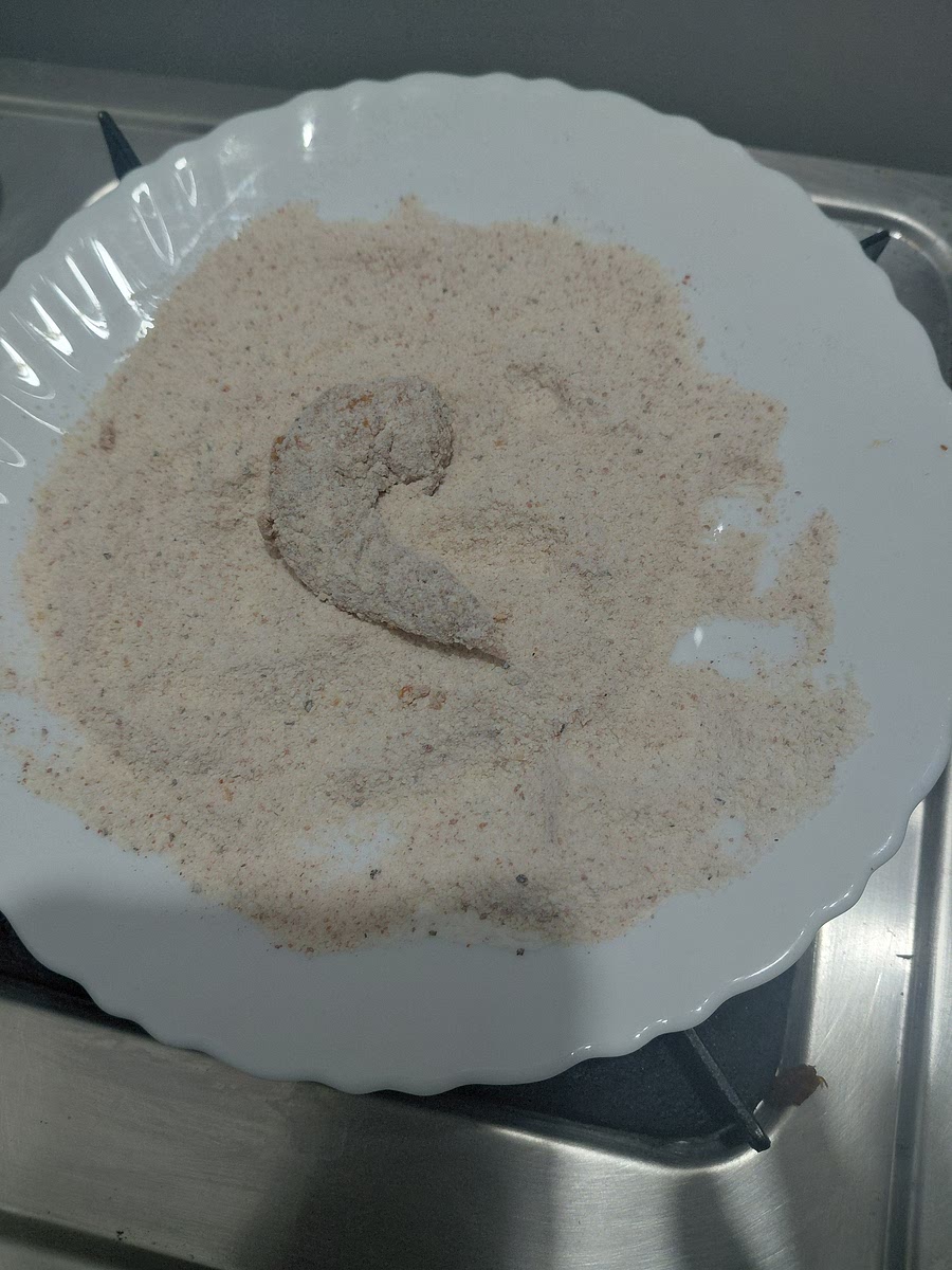 Coat the prawns in batter. Dust off the excess.