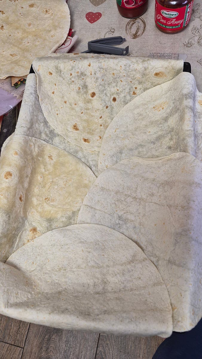 Pana scade apa la carne, tapetez o tava mare cu 7 foi de tortilla si dau drumul la cuptor la 200 de grade sa se incalzeasca
