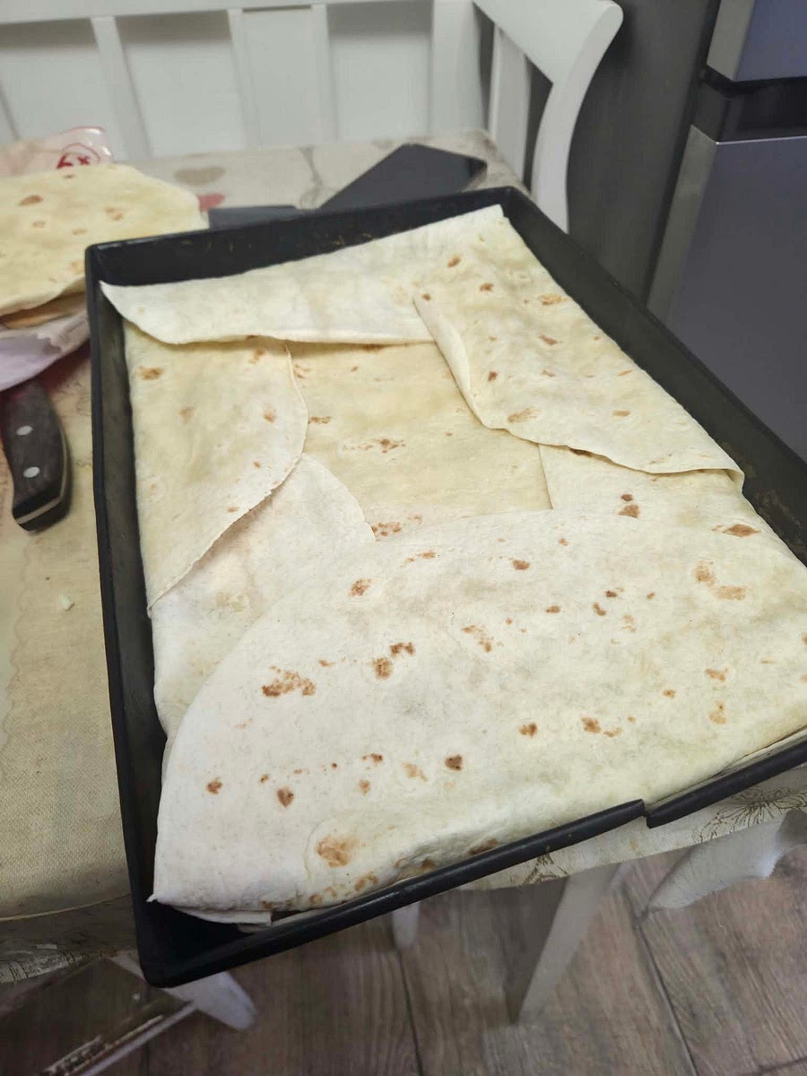 Dupa ce carnea e gata o pun in tava si nivelez cat de uniform, pun peste casul razalit, pun o foaie de tortilla peste toate, pe mijloc, apoi impachetez compozitia. Topesc untul si-l ung peste tortilla. Bag la cuptorul incins aprox 15 minute