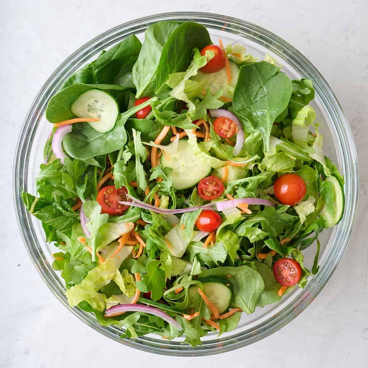 Prepare the vegetables. Chop the lettuce, spinach, tomatoes, cucumber and onion. Grate the carrot. Slice the avocado and quarter the boiled eggs.