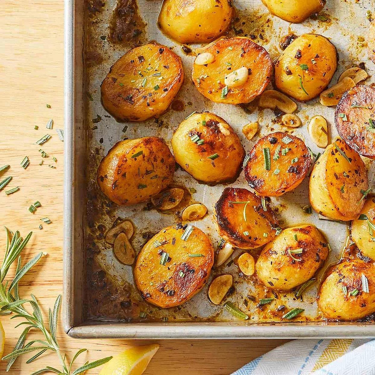 Prepare the garlic baby potatoes. Preheat the oven to 210°C. Cut the potatoes in half, leaving their skins on. Toss with olive oil, rosemary, garlic, salt and pepper. Spread on a baking tray, cut sides down, and roast for 30–35 minutes until golden and tender. Turn if needed.