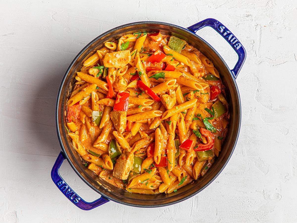 Cook the pasta in the sauce. Add the uncooked penne, chopped tomatoes and chicken stock. Stir well, cover and bring to a gentle boil. Reduce the heat and simmer for approximately 10–14 minutes, stirring frequently. Add a splash of extra stock or water if the sauce becomes too thick before the pasta is cooked. Gluten-free pasta can soften quickly, so begin checking it a few minutes before the package's recommended cooking time. Ensure the chicken reaches 74°C internally.