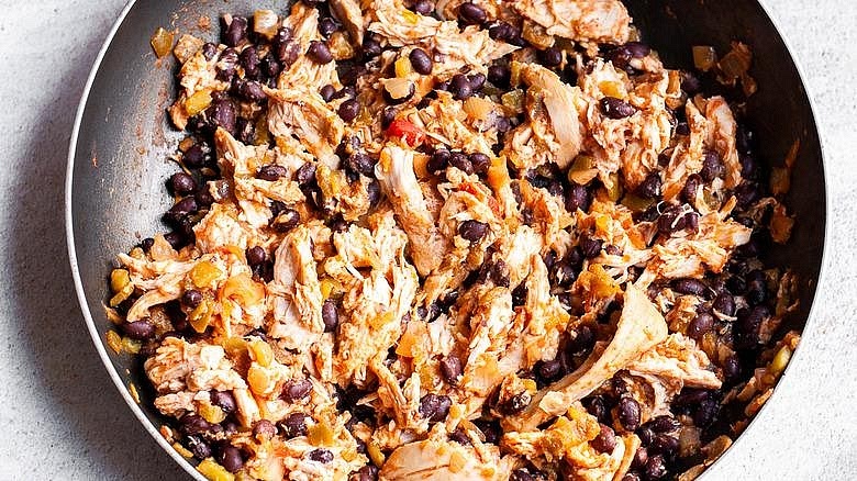 Make the enchilada filling Using the same pan, sauté the chopped yellow onion for 3–4 minutes until softened. Add the fresh garlic and cook for another 30 seconds. Stir in the drained black beans and diced green chillies. Add the shredded chicken and a few tablespoons of the enchilada sauce. Mix until the filling is moist but not watery.