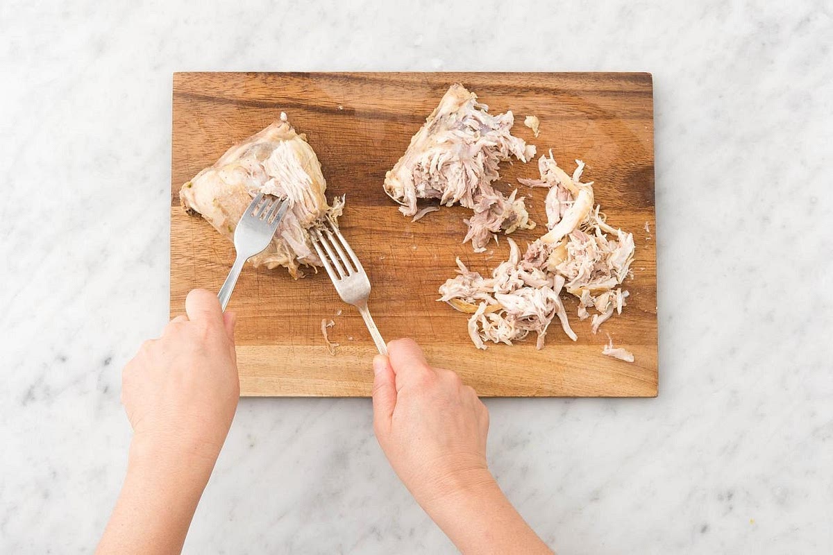 Shred the chicken Carefully remove the cooked chicken to a clean board. Use two forks to shred it into bite-sized pieces. Remove the bay leaf from the soup. Keep the chicken aside while preparing the noodles.