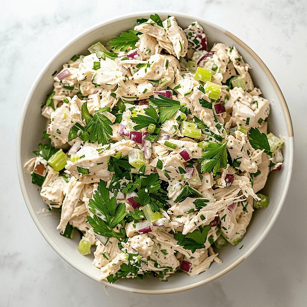Prepare the creamy chicken salad Place the cooked shredded chicken in a mixing bowl. Add the mayonnaise, dairy-free yoghurt, brown mustard, diced red onion, celery, parsley, lemon juice, salt and black pepper. Mix gently until all the chicken is coated in the creamy dressing. The filling should be moist and creamy, not overly runny. Add a little extra mayonnaise or yoghurt if needed.