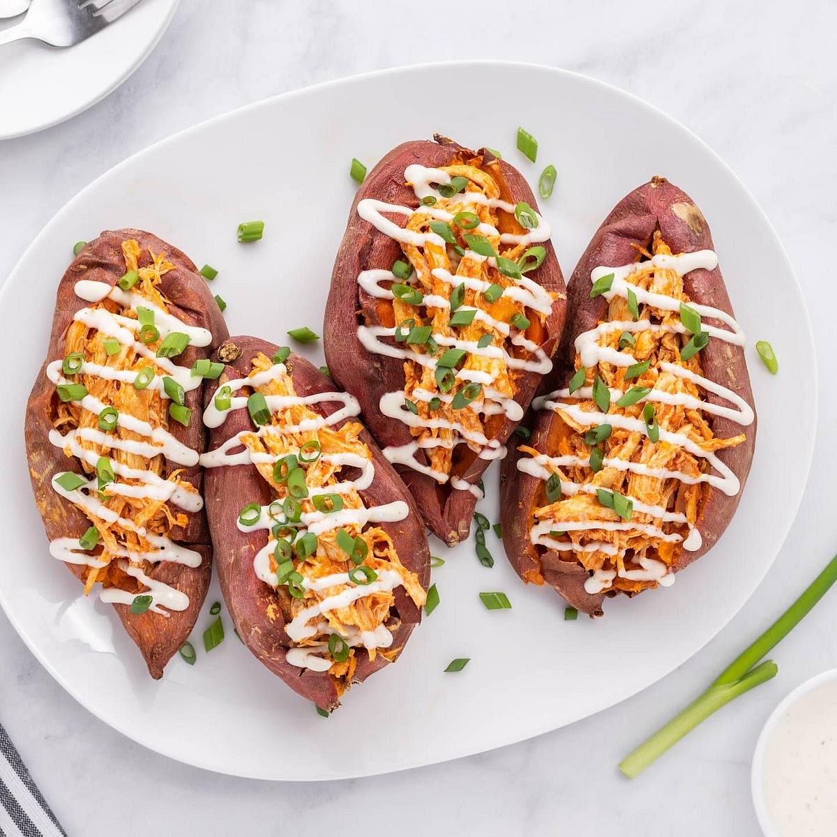 Stuff the sweet potatoes Turn the roasted sweet potatoes cut-side up. Fluff the flesh gently with a fork, creating a shallow hollow in each half. Spoon the warm, creamy buffalo chicken filling generously over the sweet potatoes. Garnish with sliced spring onions or chives.