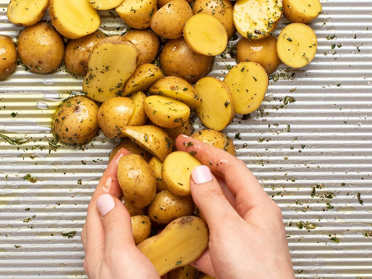 Roast the garlic-herb potatoes Preheat the oven to 200°C. Toss the halved baby potatoes with olive oil, minced garlic, thyme, rosemary, oregano, salt and black pepper. Arrange cut-side down on a large baking tray. Roast for approximately 15 minutes before adding the vegetables.