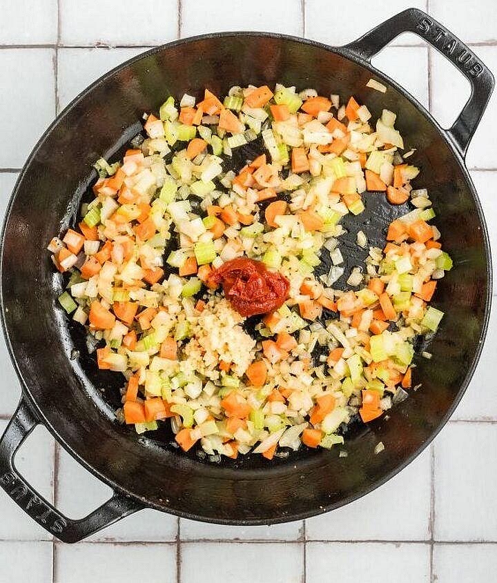 Prepare the aromatic tomato base In the same pan, add the onion, carrot, celery and mushrooms. Sauté for 3–4 minutes, allowing the vegetables to soften. Add the garlic and tomato paste. Cook for another minute until fragrant. Stir in a splash of the beef stock to release the browned bits from the pan. Transfer everything to the slow cooker.